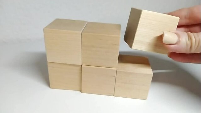 Math count for addition 5+1=6
A man builds a structure out of wooden blocks, stacking wooden blocks by hand. Business concept for success growth process.
