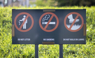 An information sign showing prohibition signs at the entrance to the park on a sunny summer day. Do...