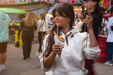 woman holding Belgian french fries with sauce at food court. street food festival on background blurred