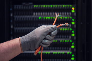 Network wires in the hands of a man at the server for data storage, close-up