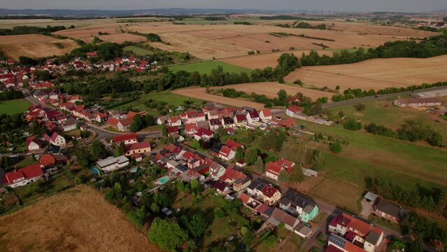 Aer ial view of a German village surrounded by meadows, farmland and forest in Germany.