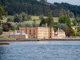 Beautiful view of the Port Arthur Historic Site building by the water with forest trees, Australia