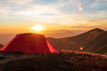 Red hiking tent on the mountain top at the sunset. © Mny-Jhee