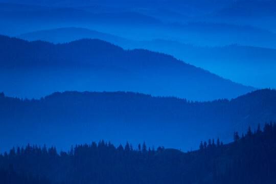 Blue misty mountain silhouettes in the morning. © Mny-Jhee