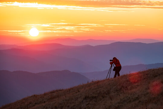 Travel photographer with professional gear makes photos of the sunset