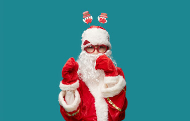 Child boy in a festive costume of Santa Claus on a turquoise background in glasses for a party