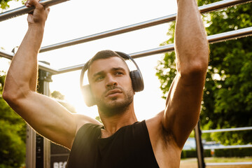 Young man listening to music with headphones during workout in park