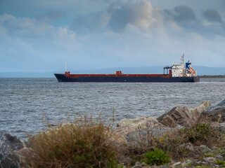Cargo ship leaving port. Commercial carrier vessel delivering goods and products by water. Import...