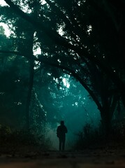 Silhouette of a person in a forest in blue colors - loneliness concept, vertical shot