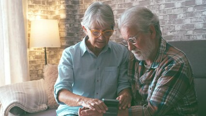 Close up and portrait of old woman checking pressure of his husband at home sitting not he sofa. Mature man feeling bad and sick measuring hypertension with a machine.