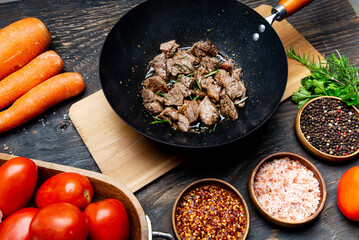 Beef fillet fried with vegetables in a wok. Argus in the wok. Top view of the kitchen table with spices and vegetables.