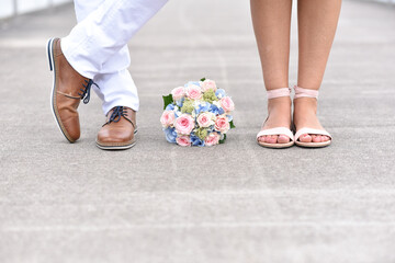 Bride and groom are standing next to the bridal bouquet, close-up photography of leg and shoes