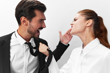 Man and woman pulling on tie anger business looking at each other screaming with hands up in white isolated background. The concept of business in a couple harassment startup copy space