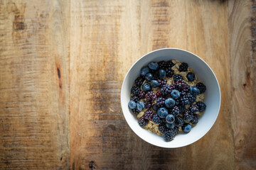Fototapeta na wymiar oats, blackberries and blueberries in a bowl on wooden table