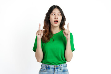 Fototapeta premium Beautiful confident Asian woman in green empty t-shirt isolated on white background. Point your finger to copy space to introduce products or services