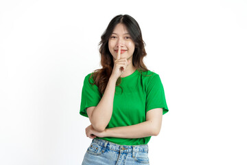 Beautiful confident Asian woman in green empty t-shirt isolated on white background. Use your index finger to cover your mouth with a lie or not loudly concept