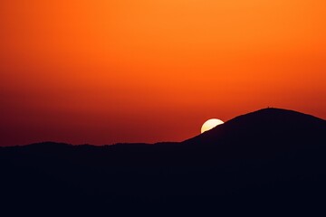 Sun setting behind a silhouette mountain in , Athens, Greece