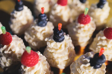 Beautiful multicolored decorated baked sweet tasty candy bar dessert on kids children party with happy people around, catering banquet table on a kids children party