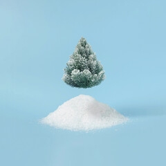 Creative layout with snowy Christmas tree on bright blue background. Minimal winter nature holiday scene