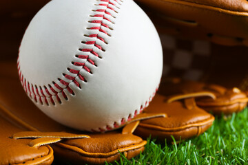Catcher's mitt and baseball ball on green grass, closeup. Sports game