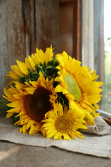 Beautiful sunflowers on cloth near window indoors