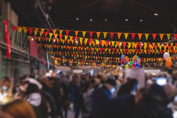 Crowded Christmas market with New Year decorations and multicolored flags, balloons, garlands and...