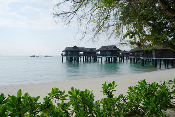 Beautiful wooden stilt houses along Pangkor laut with clean bean and lush greenery.