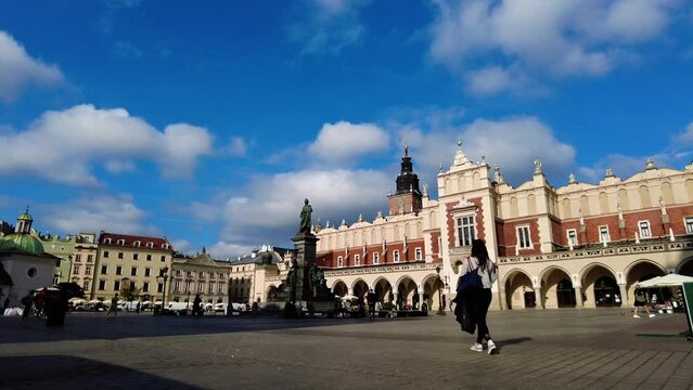 Female Tourist Walking On The Main Market Square With Adam Mickiewicz Monument In Cracow, Poland. Slow Motion