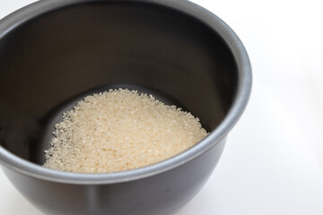 炊飯器の黒い釜の中に生の白い米粒