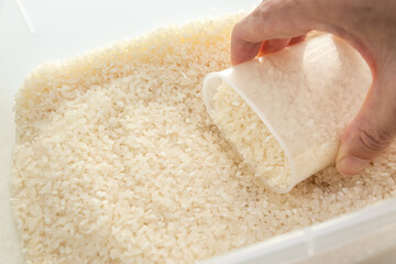 米びつの中のお米を計量カップですくう