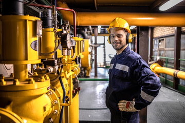 District heating plant interior and experienced technician standing by gas pipeline energy source.