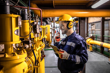 Natural gas refinery plant interior and an engineer standing by energy source pipeline.