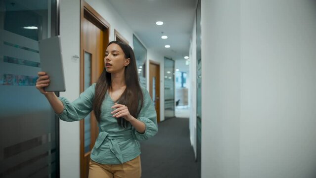 Positive woman speaking on video call hallaway closeup. Manager walking waving