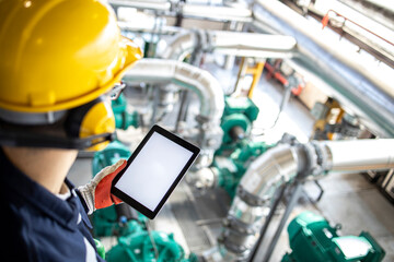 Petrochemical engineer or technician holding digital tablet and controlling crude oil processing inside refinery.