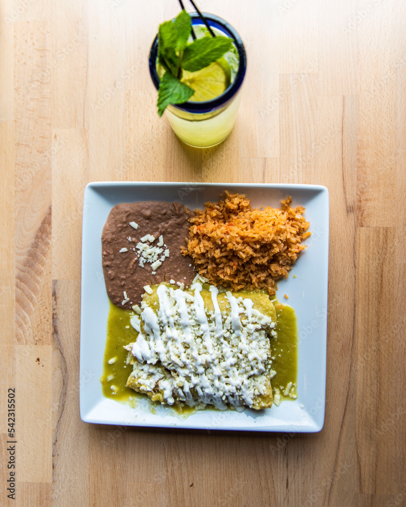 Wall mural top view of enchilada with mojito on a wooden surface