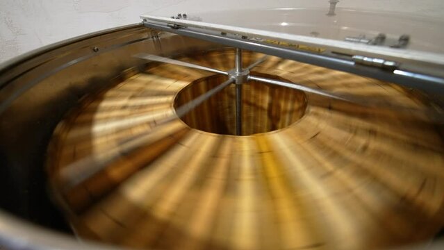Honey removal machine rotating the frames with organic honey. Harvesting healthy product on the rural bee farm. Close up.