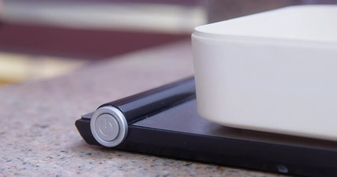 Dog paw presses the button, turns on electronic scales with plastic container weighs the food on them. Cook according to recipe measure. Eating behavior healthy lifestyle food diary, counting calories