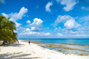 Beautiful tropical scenery. Young man walking on a lonely beach.