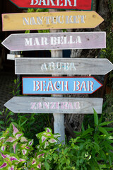 Wooden hand-painted signs of direction to many places in a resort. Colorful art craft piece with a local sense.