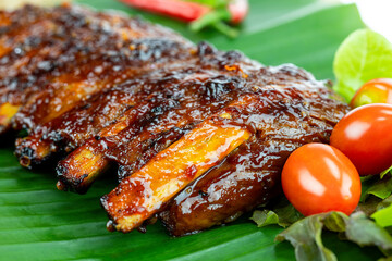 Grilled pork ribs placed on banana leaves.