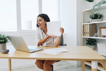 Woman business freelancer via video link via laptop shows papers online for startup, smile and happiness in employee chat