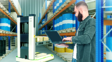 Fototapeta na wymiar Warehouse technologies. Man with laptop in warehouse building. Robotic forklift concept. Guy is developing robotic forklift. Man and warehouse racks. Robotic forklift technology. Art blurred
