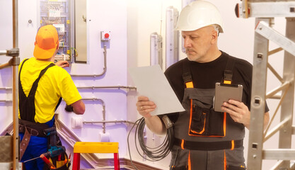 Man electrician. Installation electrical equipment. Two electricians in technical room. Maintenance...