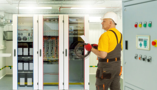 Installation network equipment. Man is Internet provider specialist. Internet company employee in front of north cabinet. Man in work uniform set up network equipment. Network technology maintenance