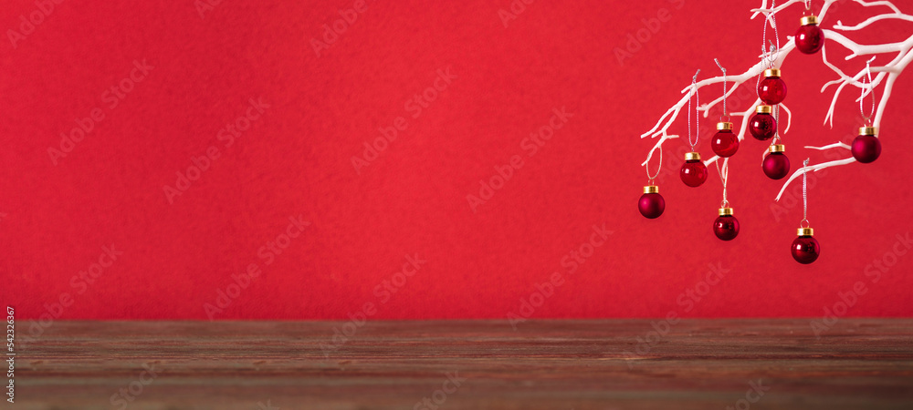 Poster merry christmas with xmas tree and bauble ball at vivid red wall at wooden table.copy space for addi
