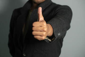 a business man in a men's business suit with a thumbs up hand gesture.