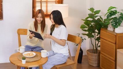 Relax at home concept, LGBT lesbian couple pointing and looking on tablet while working together