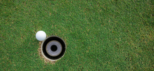 Top views white golf ball and golf hole on green grass texture background. coppy space