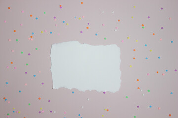 White paper with colorful confetti over pink background. 