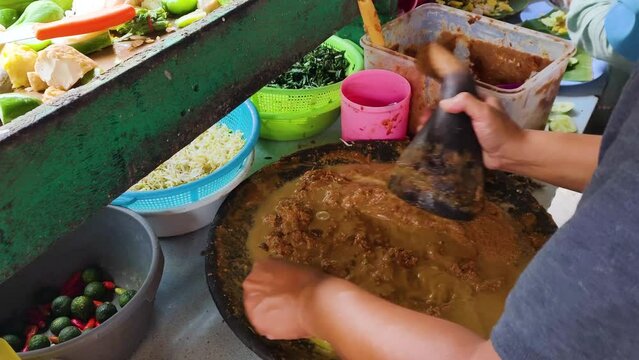 Man hands is grinding peanuts to makes Gado gado